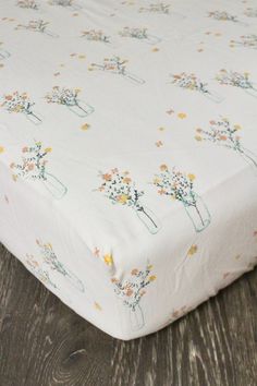 a white sheet with flowers on it sitting on a wooden floor next to a wall