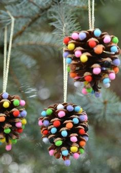 two pine cones with colored balls hanging from them