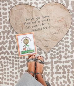 a woman's feet with sandals next to a heart - shaped paper sign that reads, before you speak home and be smart it's hard to fix a wounded heart