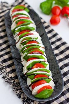 a black plate topped with sliced up veggies on top of a checkered table cloth