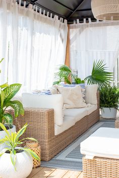 an outdoor living area with wicker furniture and potted plants on the side table