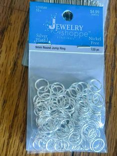 a package of silver jump rings sitting on top of a wooden table