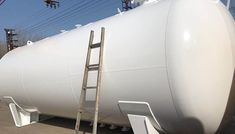 a large white tank sitting on top of a parking lot next to a power line