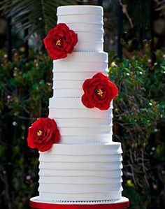 a tall white cake with red flowers on top