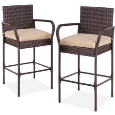 two brown wicker barstools with beige cushions on white background, one in front of the other