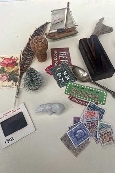 an assortment of stamps and other items on a white table with a silver spoon in the middle