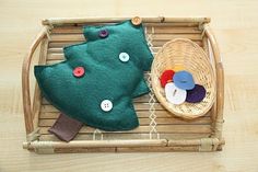 a small green christmas tree sitting on top of a bamboo tray next to a basket