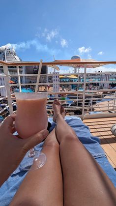 a woman laying on top of a blue towel next to a glass of drink in her lap