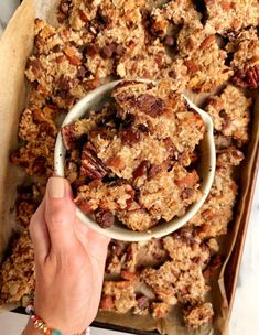 a person is holding a bowl of granola