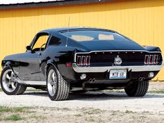 a black mustang parked in front of a yellow building