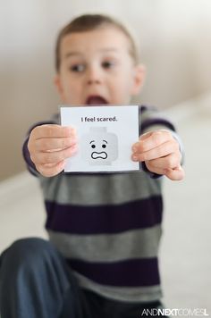 a young boy holding up a card with the words i feel scared on it