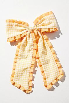 a yellow and white checkered bow tie on a white surface with the top knot undone