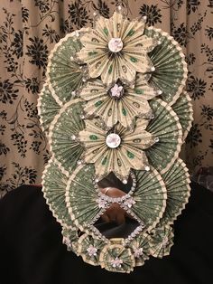 an intricately designed green and white paper fan with jewels on it's sides