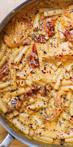 a pan filled with pasta covered in sauce and seasoning on top of a wooden table