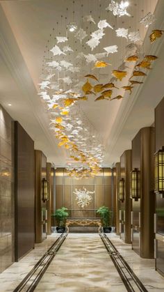 an elegant lobby with chandelier and marble flooring, along with planters