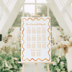 an orange and white wedding seating chart on a easel