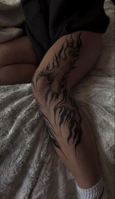 a person sitting on top of a bed with a tattoo on their leg and legs