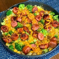 a skillet filled with broccoli, cheese and sausage on top of a blue cloth