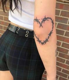 a woman with a heart tattoo on her arm and barbed wire in the shape of a heart