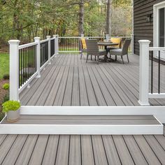 a wooden deck with white railings and chairs