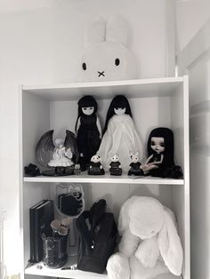 a shelf filled with dolls and stuffed animals on top of it's white shelves