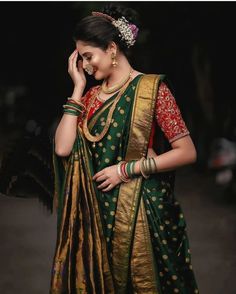 a woman in a green and gold saree talking on her cell phone while standing