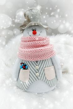 a stuffed snowman wearing a pink scarf and hat with candy in his pocket on a fluffy white background