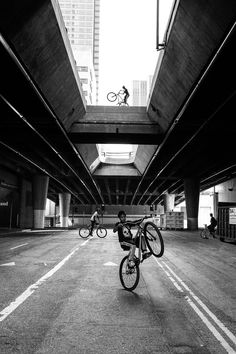 a man riding a bike down a street under a bridge