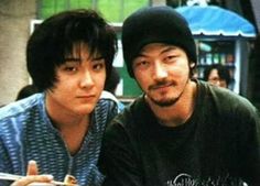 two young men sitting next to each other at a table with food in front of them