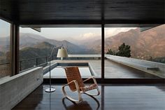 a rocking chair sitting in front of a large window overlooking the mountains and valley below