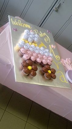 a pink table topped with cupcakes covered in frosting on top of a cake