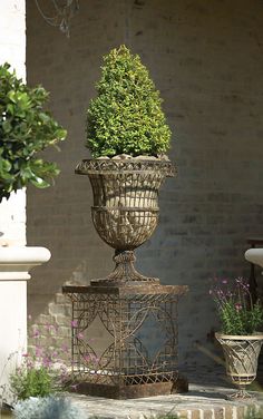 an iron planter with a potted tree in it