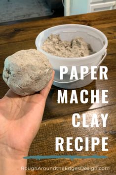 a hand holding a rock next to a bowl of paper mache clay on a wooden table