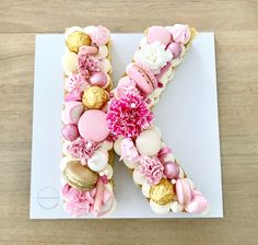 the letter k is decorated with pink and gold candies, macaroons, and other sweets