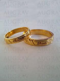 two gold wedding rings sitting on top of a white surface with words written in the middle