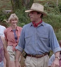 a group of people standing next to each other on a dirt road with trees in the background