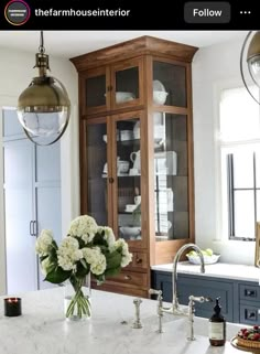 a kitchen with marble counter tops and wooden cabinetry in the center, filled with white flowers