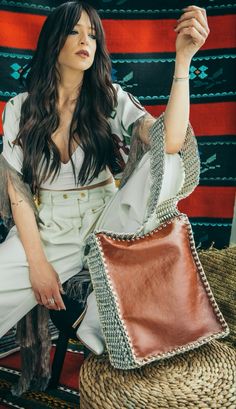 a woman sitting on top of a chair holding a brown purse in her right hand