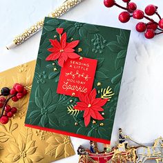 a christmas card with poinsettis and holly on it, next to other holiday cards