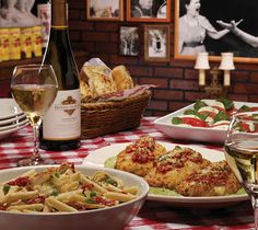 a table topped with plates of food and glasses of wine next to bottles of wine