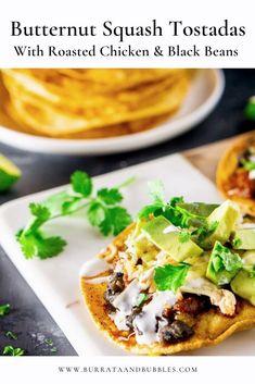 two tacos on a plate with guacamole and sour cream in the background