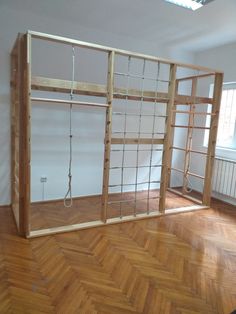 an empty room with wooden shelves and ropes hanging from the ceiling, in front of a window