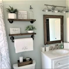 a bathroom with two shelves above the toilet and a mirror over the sink in front of it