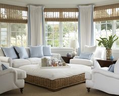 a living room filled with white furniture and blue pillows on top of it's covers