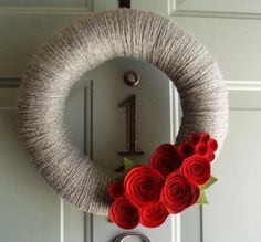 a knit wreath with red roses on the front door and number one in the middle