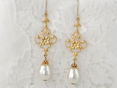 Delightfully eclectic and with an Art Nouveau flair, these earrings are delicate gold floral filigree are embellished with white Swarovski crystal pear shaped pearl dangles. They are the perfect wedding event or elopement earrings. They make for fabulous gifts for the bride, mother of the bride, or bridesmaids. Finished with 14K Gold-Filled ear wires, these are the perfect earring for sensitive ears, and for wowing the eyes. *Handcrafted design *Delicate silver finish over filigree *Crystal pear Elegant Gold Flower Earrings For Wedding, Gold Dangle Flower Earrings For Wedding, Delicate Yellow Gold Bridal Earrings For Wedding, Delicate Gold Chandelier Earrings With Pearl Drop, White Brass Pearl Earrings For Wedding, Gold Brass Pearl Earrings For Wedding, White Dangle Bridal Earrings With Intricate Design, Delicate Brass Wedding Earrings, White Bridal Dangle Earrings With Intricate Design