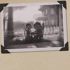 an old black and white photo of two children sitting at a table in front of a house