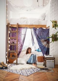 a woman sitting on the floor in front of a bed with a ladder over it