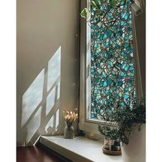 a stained glass window sitting on top of a white shelf next to a potted plant