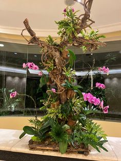 a tree with pink flowers and green leaves in a lobby area at an office building